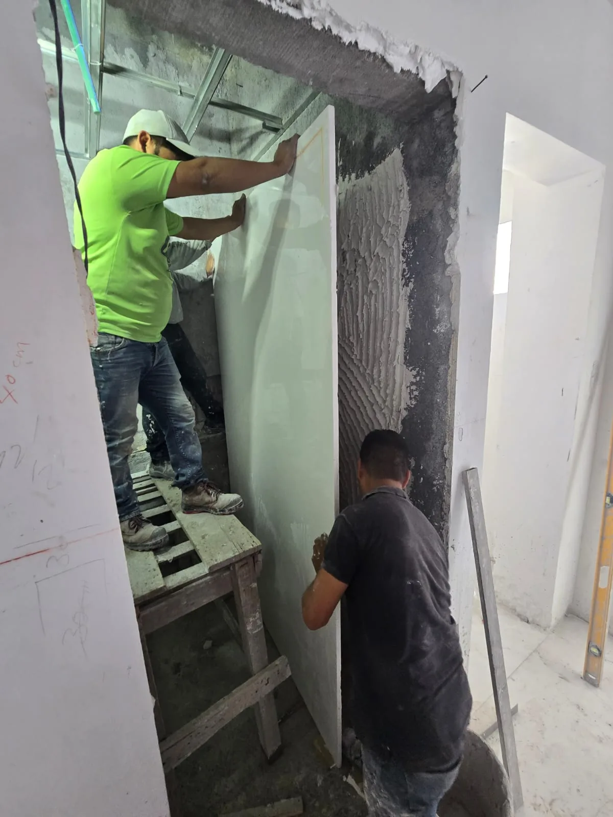 Equipo colocando una placa de gran formato sobre muro preparado
